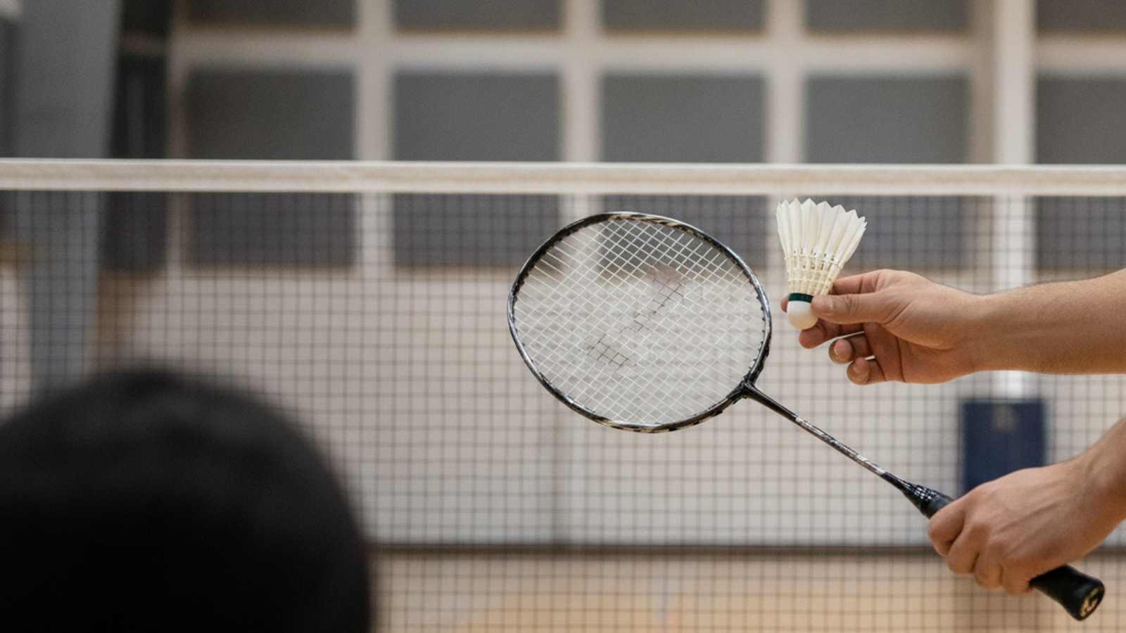 badminton coach demonstrating racket grip during a Dubai kids lesson