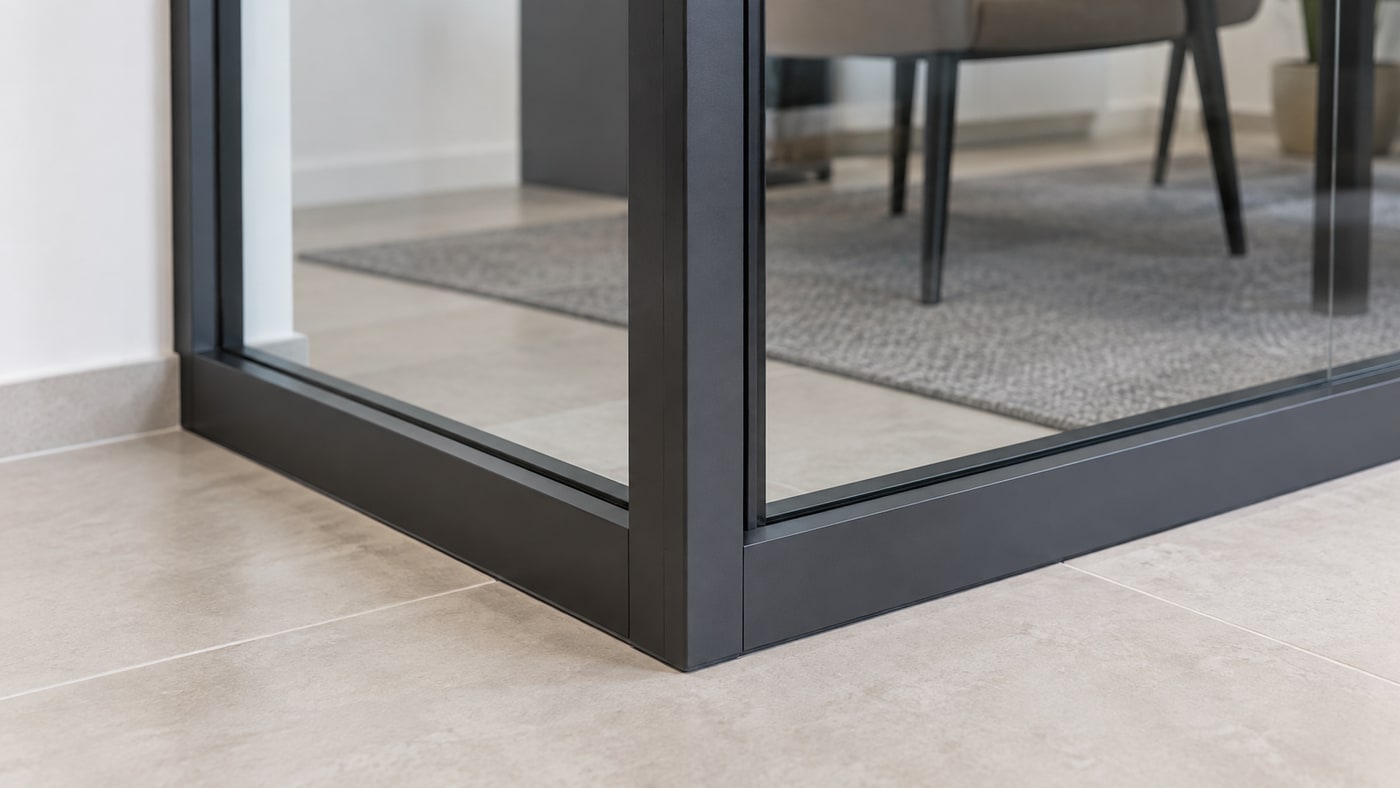 Black aluminium corner frame and lower glazing channels of an interior glass partition