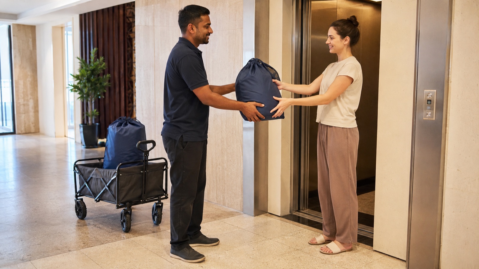 Resident handing a closed laundry bag to a collection worker beside a Dubai apartment lift